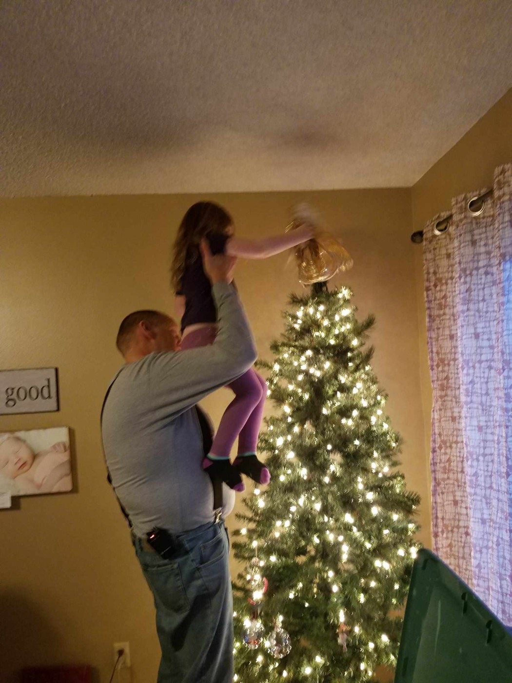 Tom lifting a child to decorate a Christmas tree