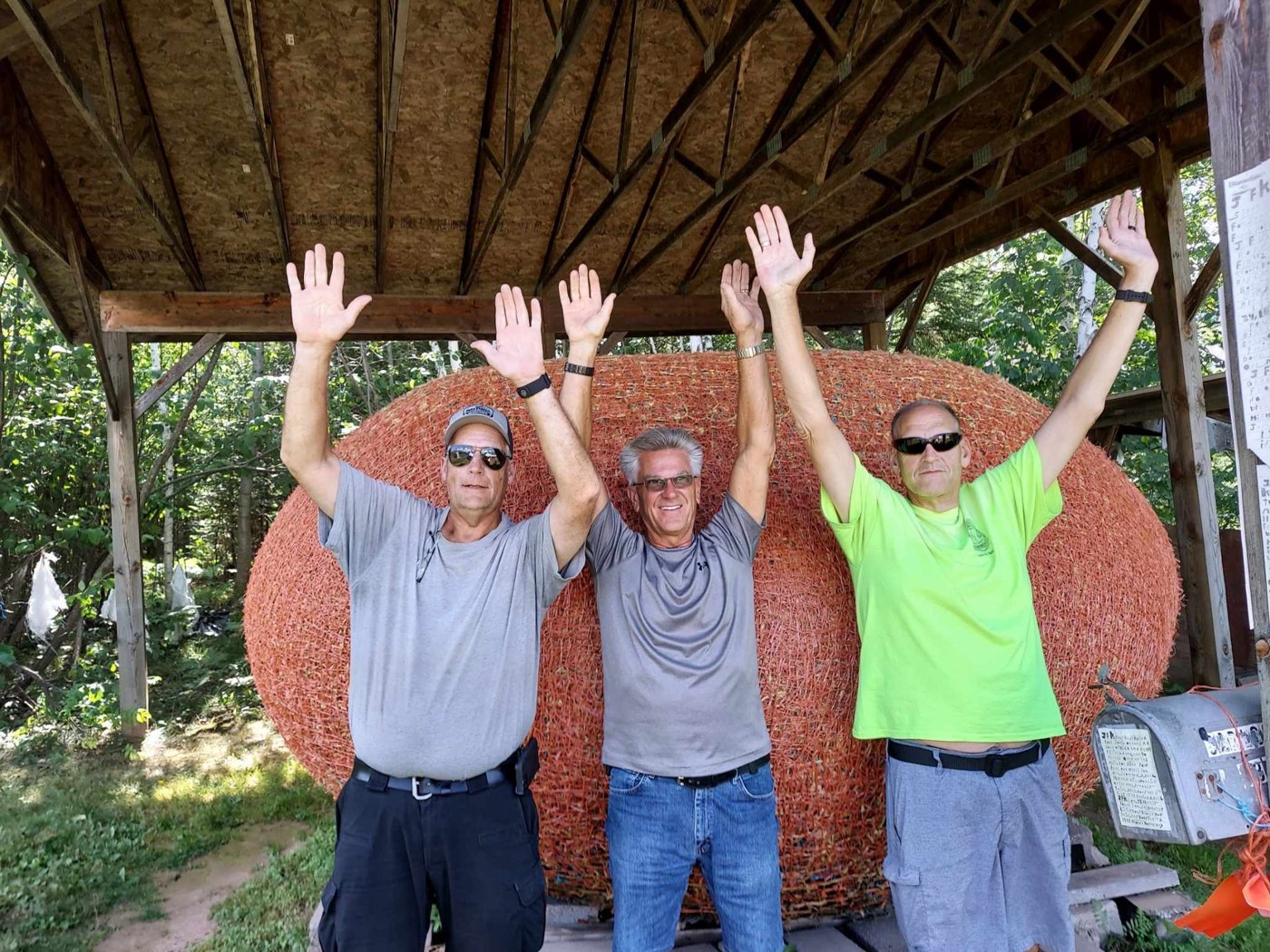 Tom and two companions raising their arms and smiling outdoors