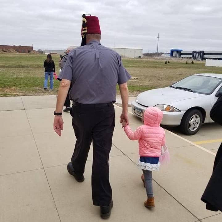 Tom holding a young child’s hand as they walk together