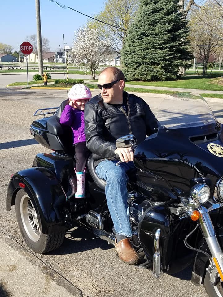 Tom and a child sitting together on his motorcycle