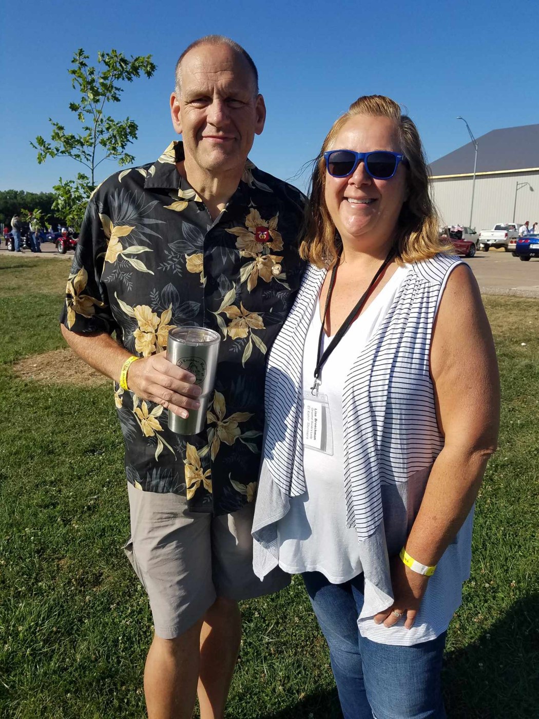 Tom standing outdoors beside a loved one on a sunny day